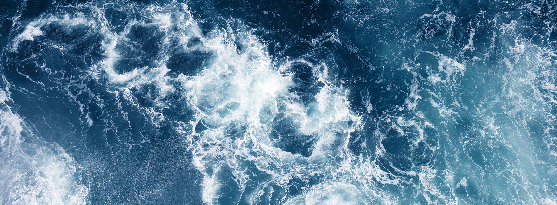 The image shows a close-up of ocean waves with the horizon line visible, creating a contrast between the rough texture of the water and the smoothness of the sky.
