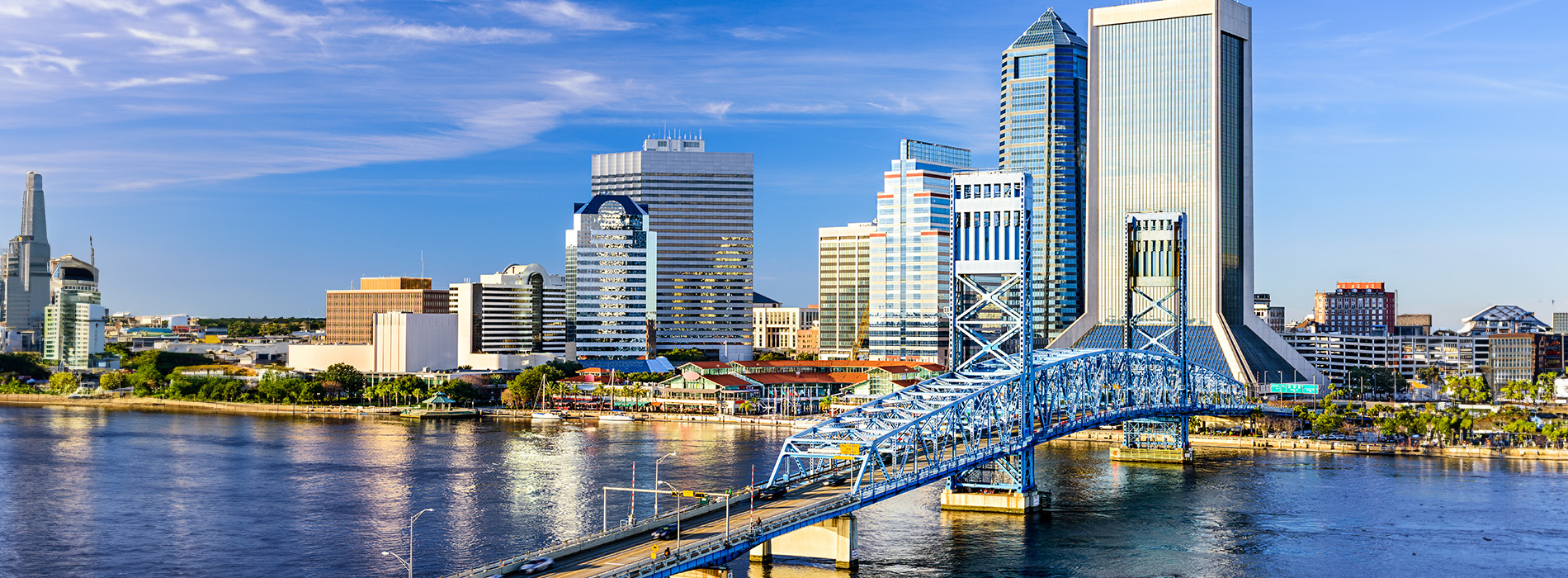 A cityscape with a large body of water, a bridge, and buildings, featuring a clear sky.