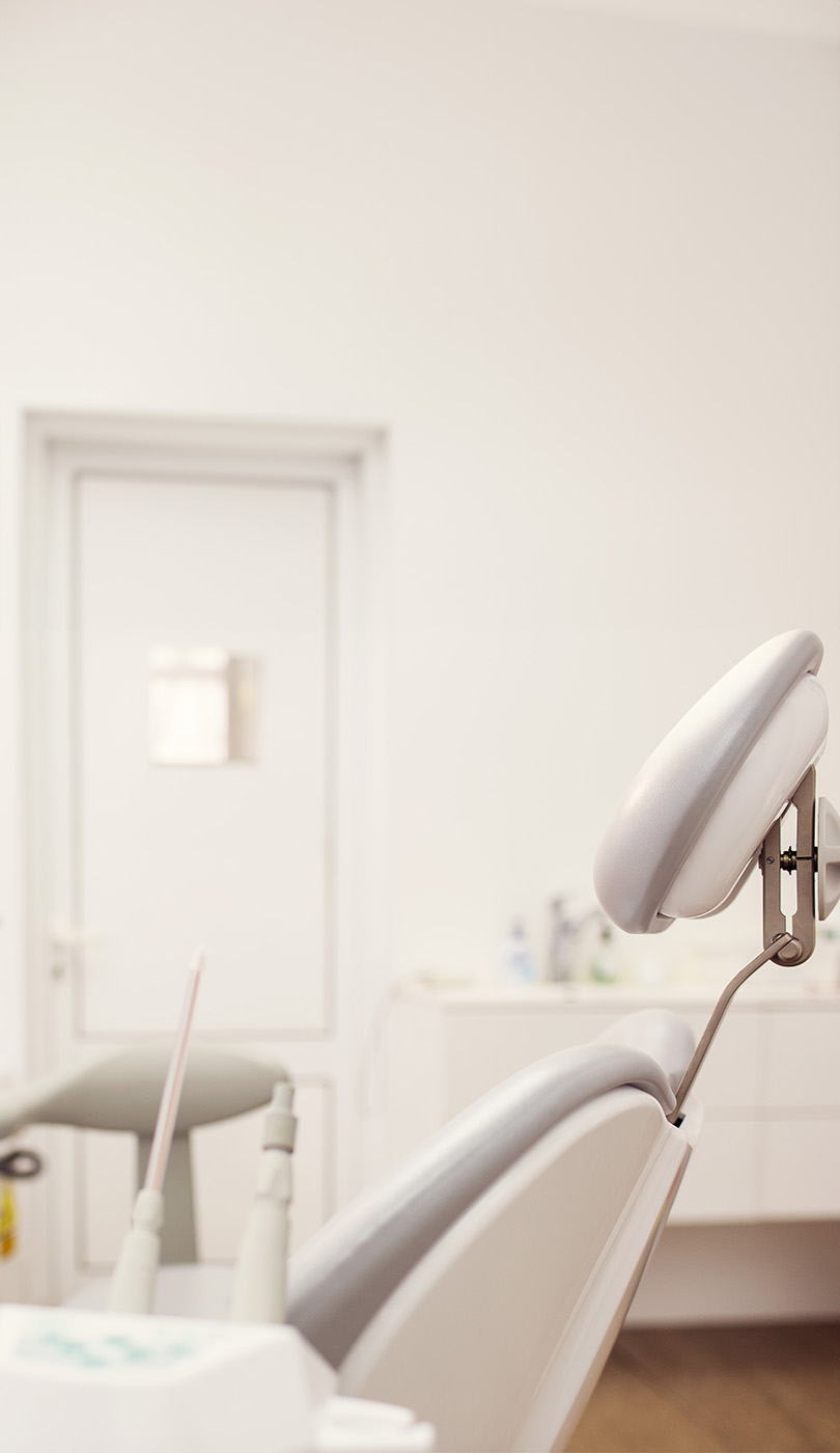 The image shows a modern dental or medical office interior with a dental chair, equipment, and a clean, professional environment.