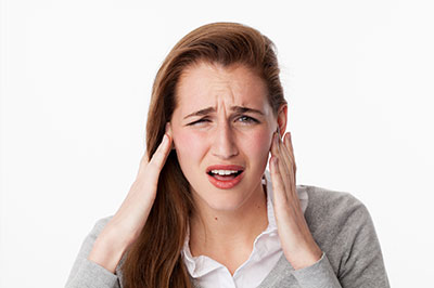 A woman with her hand on her head, appearing to be in pain or discomfort.